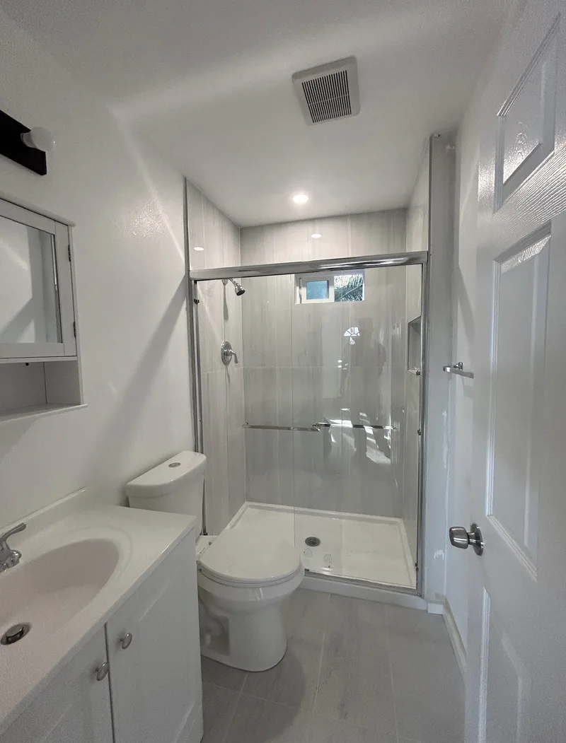 Finished modern bathroom with glass shower enclosure and white vanity